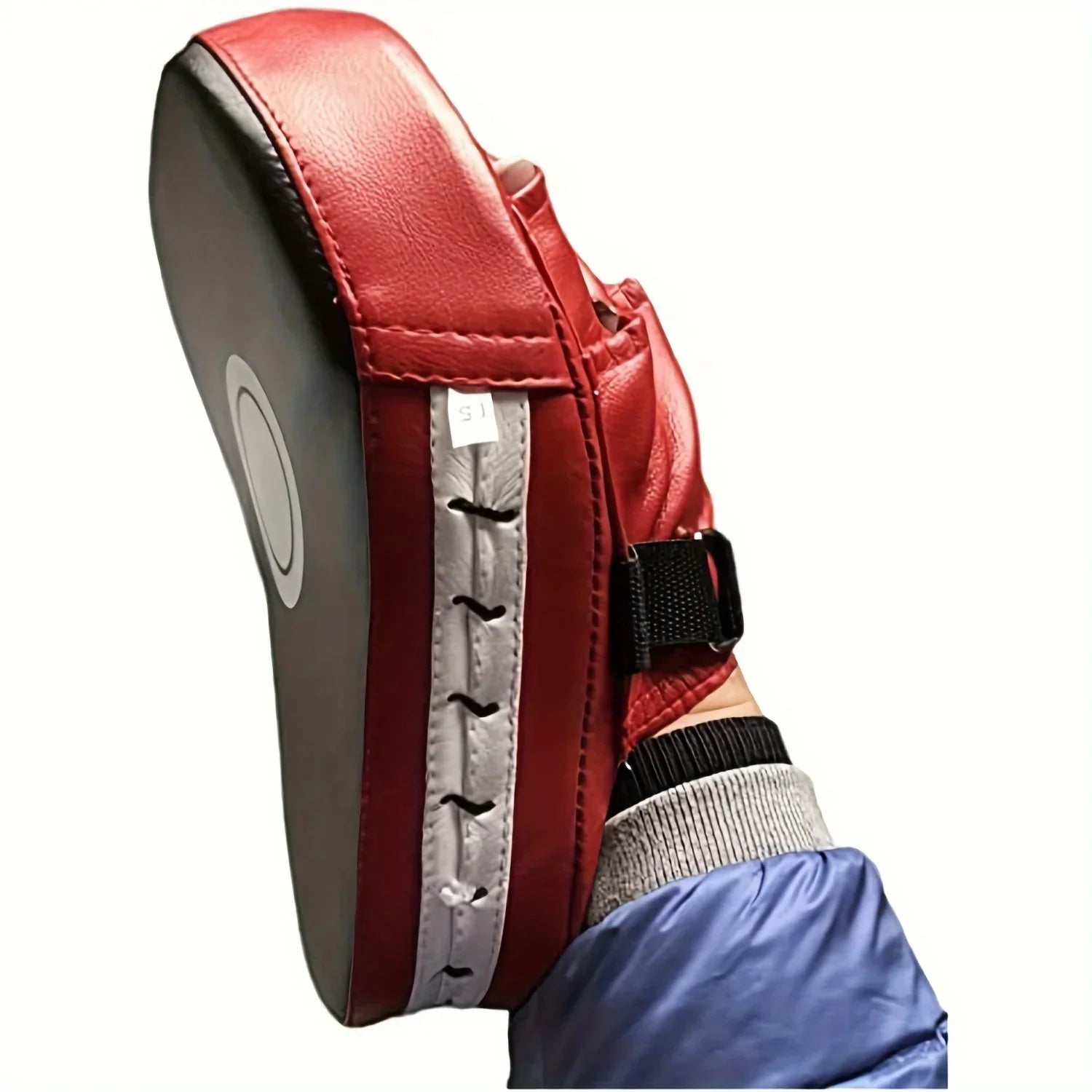 Paquete de golpeo rojo para entrenamiento de boxeo sostenido por una mano con manga azul
